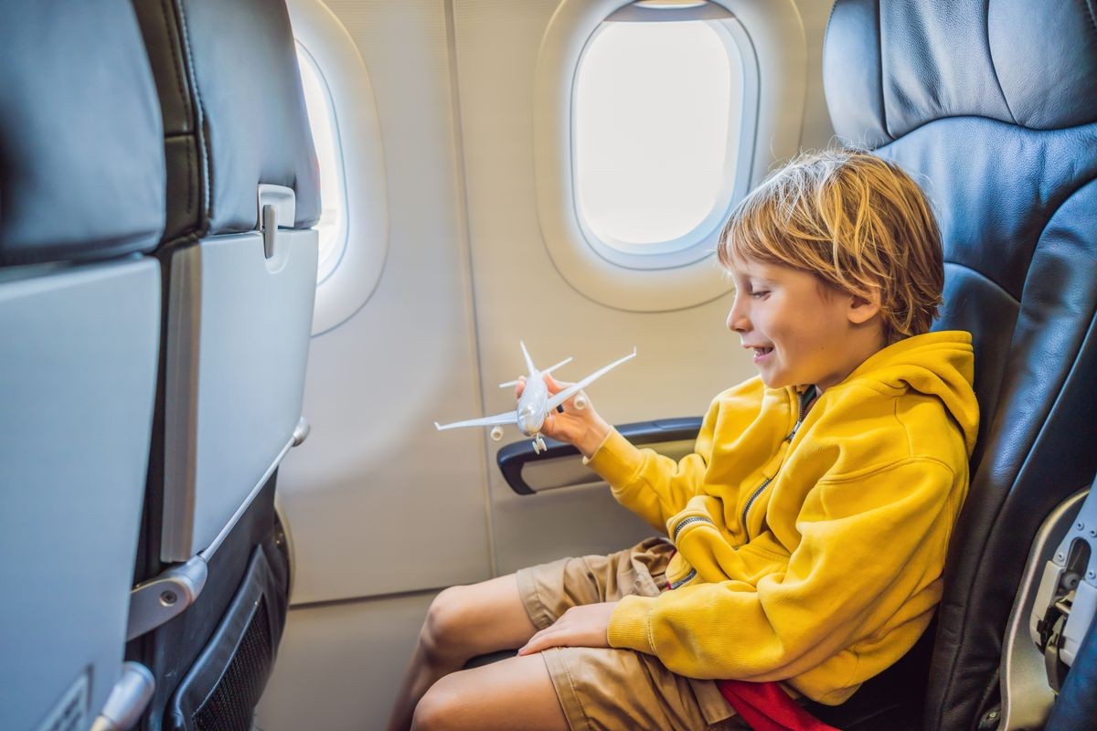 Little boy play with toy plane in the commercial jet airplane flying on vacation