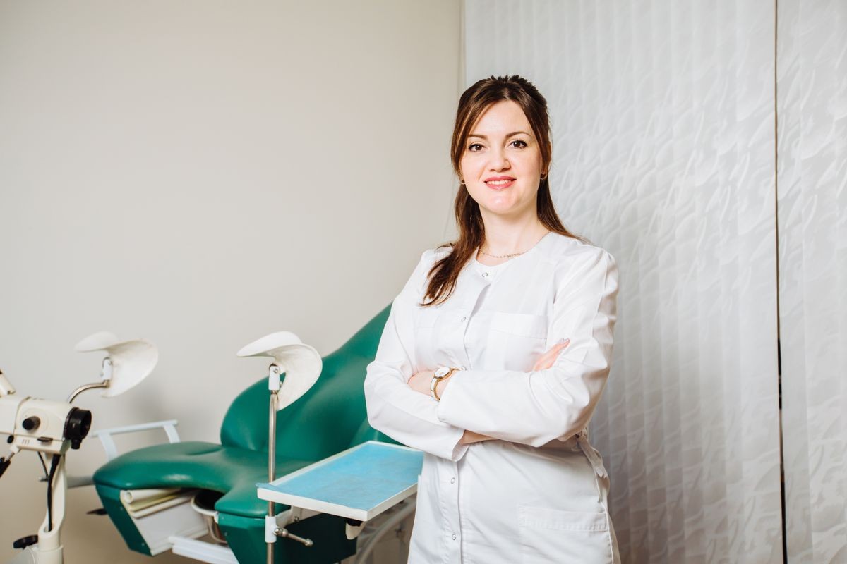 Professional brunette female doctor on modern consulting room background. Gynecology, women's health concept.