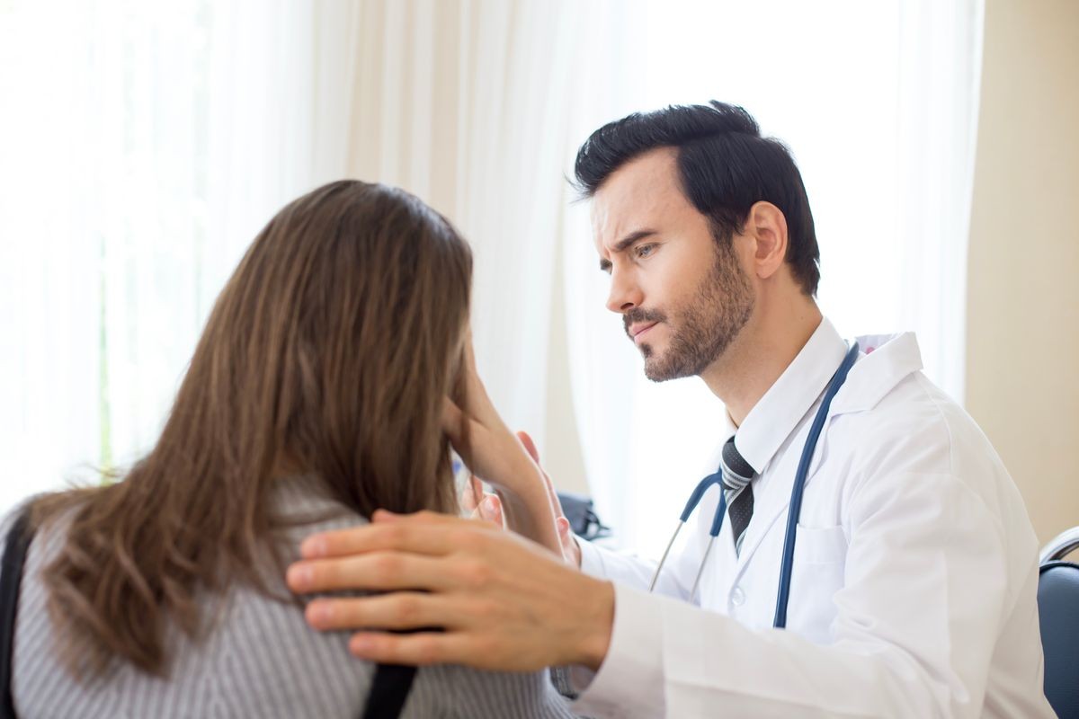 Attractive Doctor working at hospital. Doctor try to treat woman for any problem. He holding her hand.